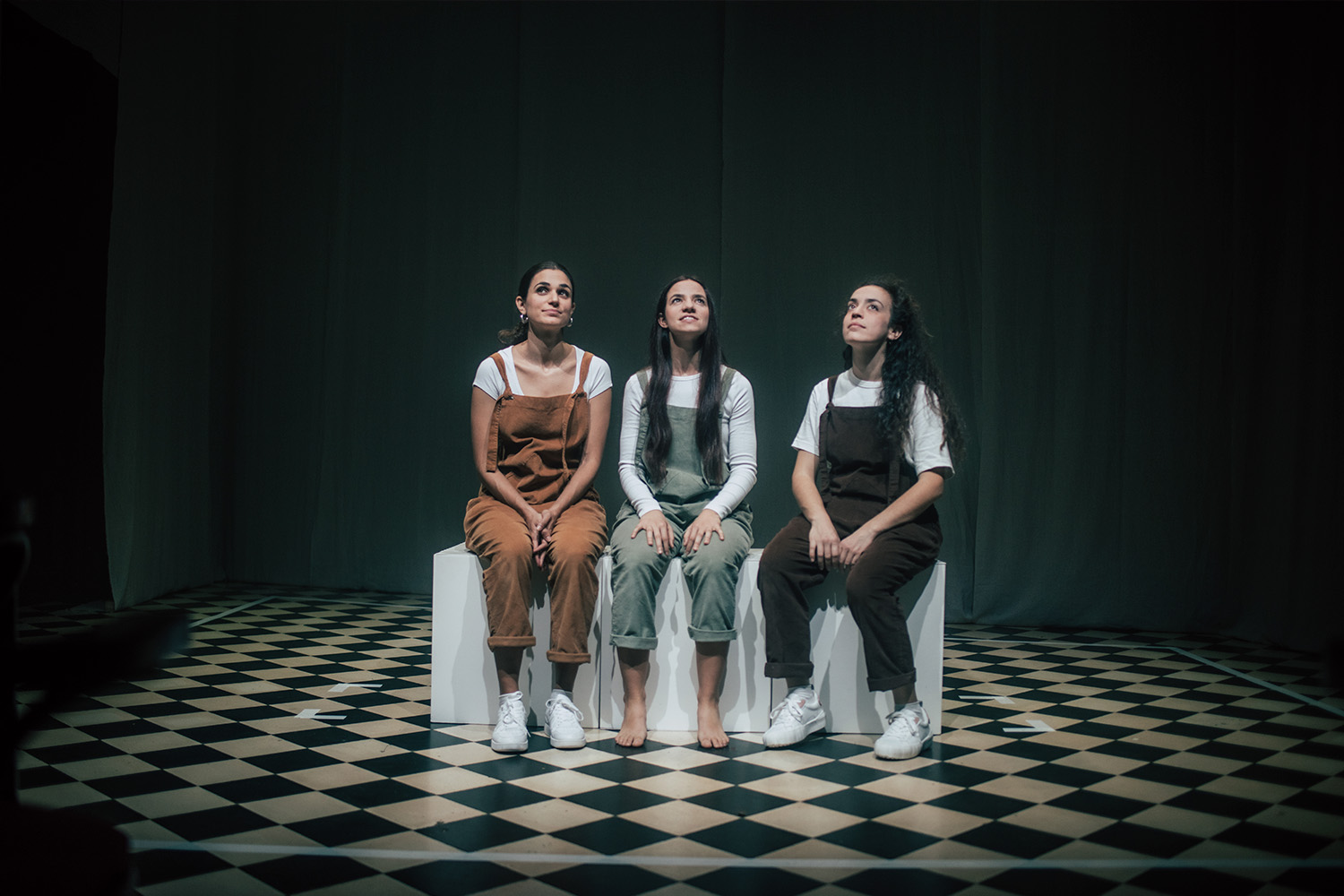 Les tres intèrprets de l'espectacle, assegudes una a costat de l'altra damunt uns cubs de fusta blancs, enmig de l'escenari
