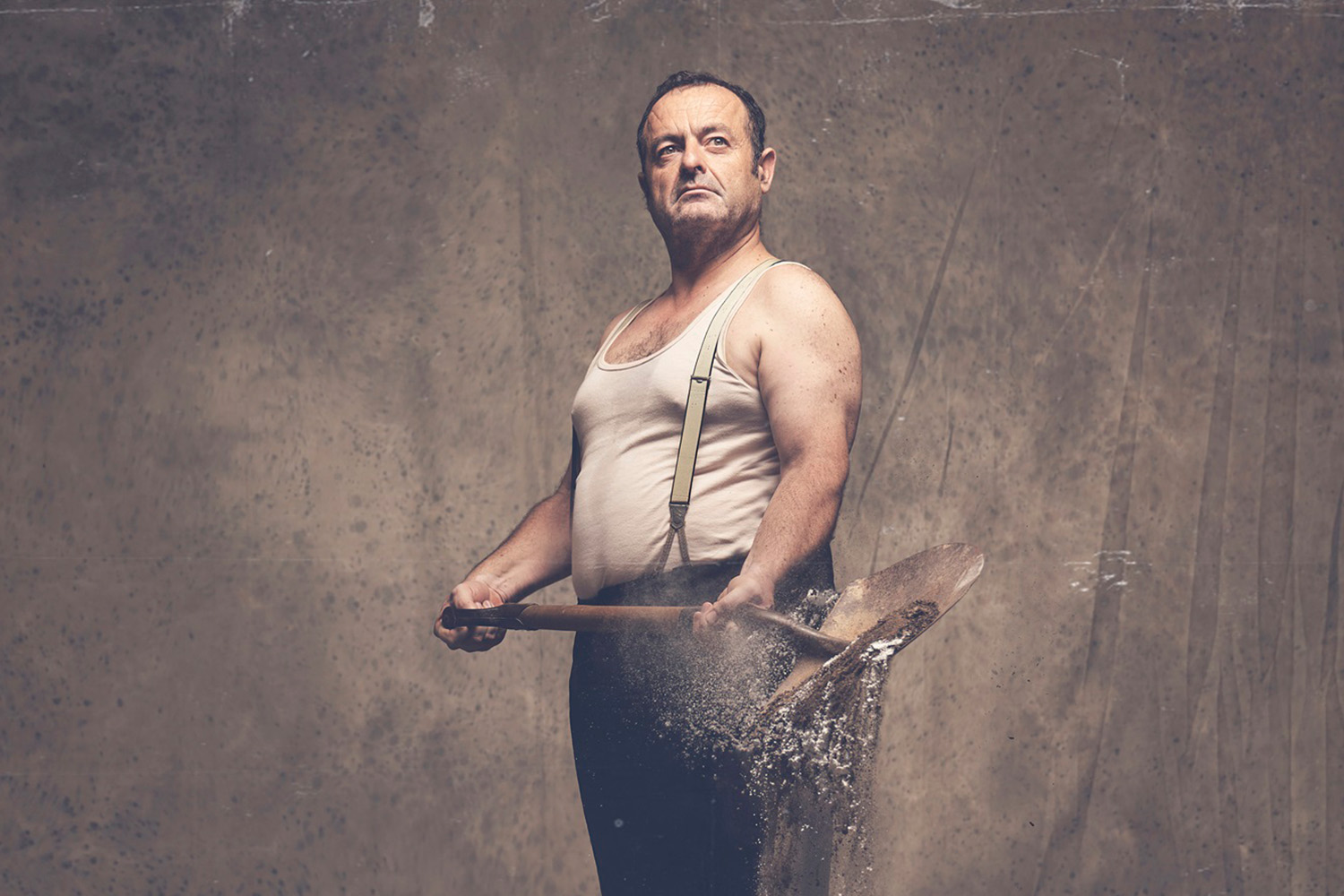 L'actor Pepe Zapata, vestit amb una samarreta imperi i uns pantalons amb tirants, sostè una pala d'on cau terra, amb la mirada seriosa