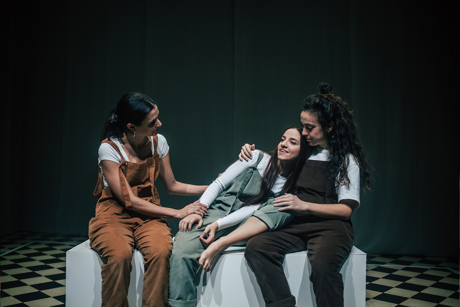 Les tres intèrprets de l'espectacle, assegudes una a costat de l'altra damunt uns cubs de fusta blancs, abraçant-se