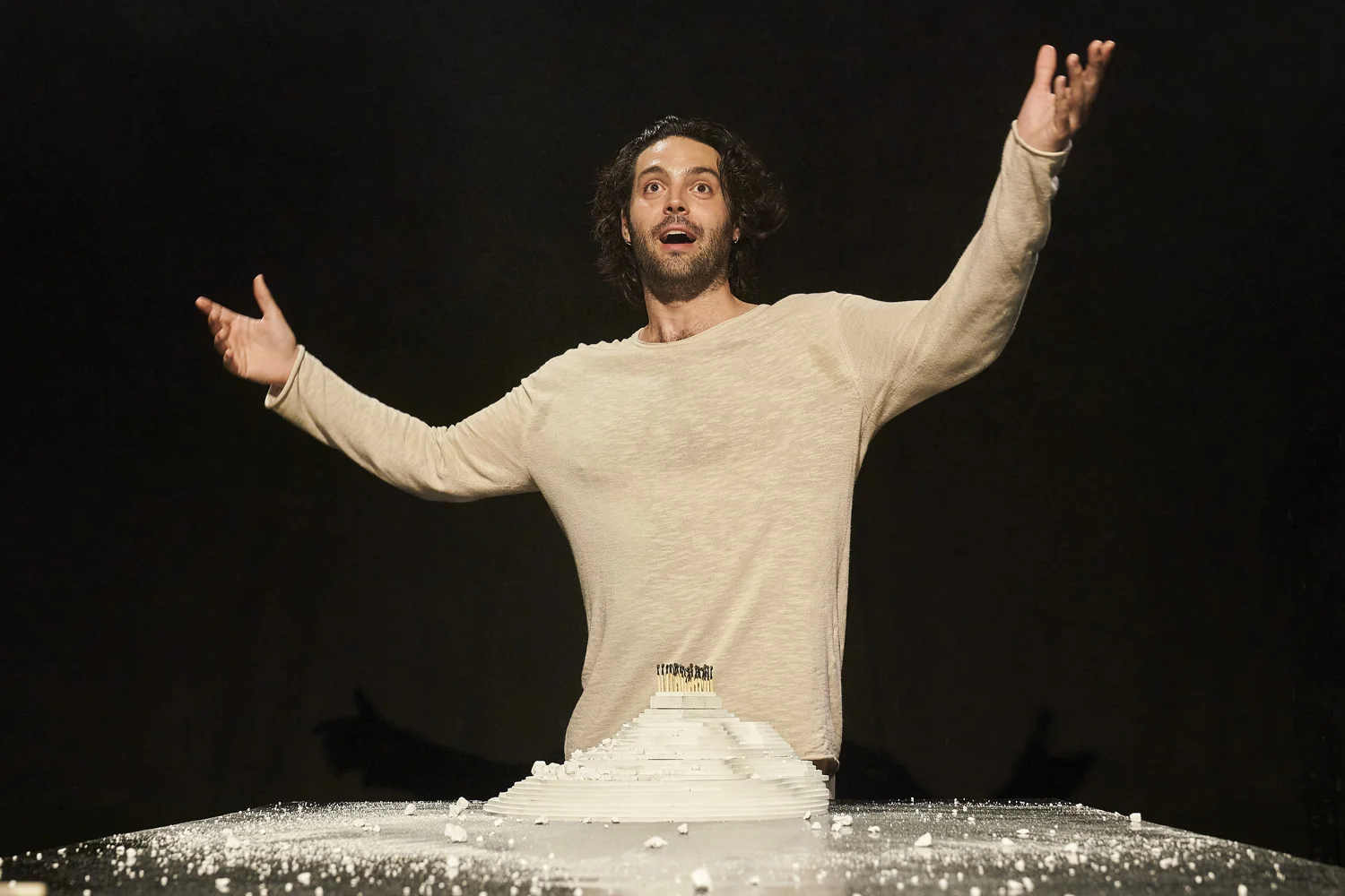 L'actor Pablo Macho Otero, vestit de blanc i amb els braços enlaire amb cara de sorpresa