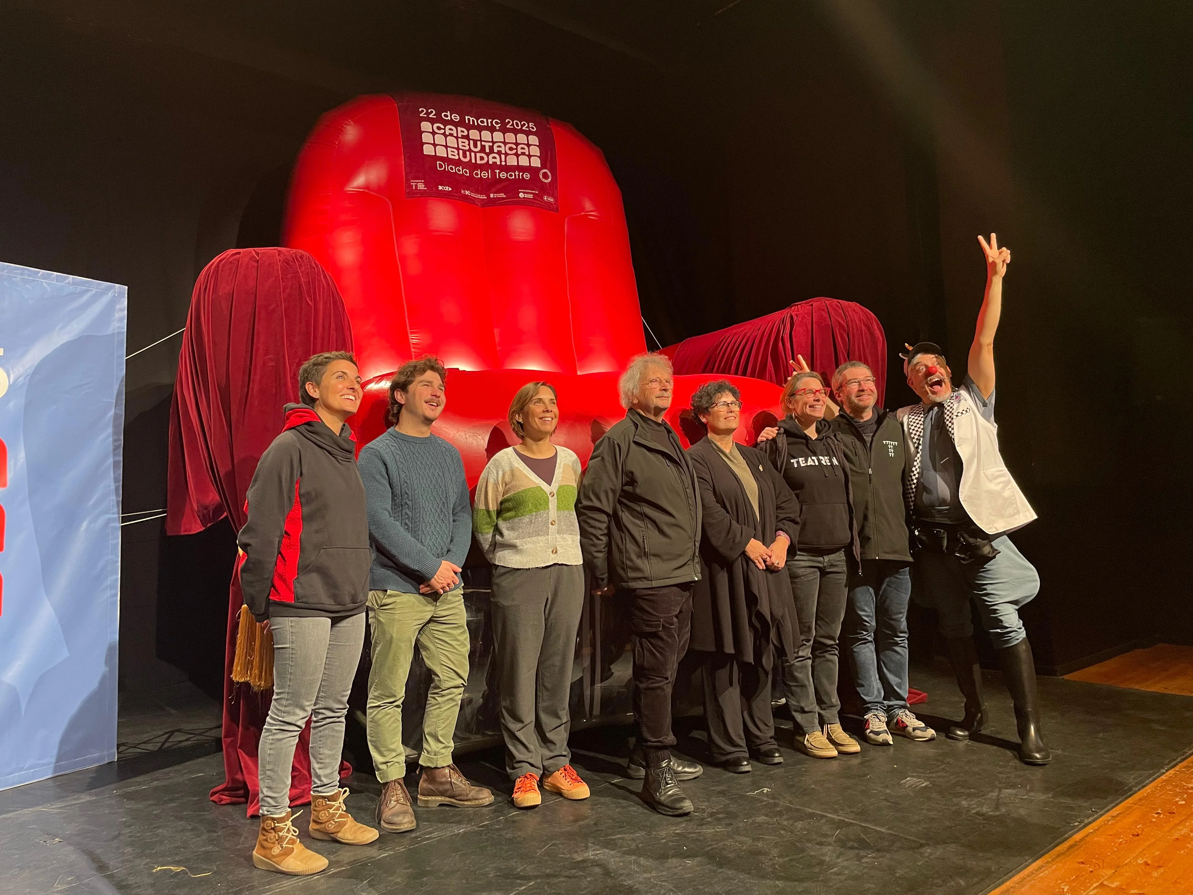 Diversos participants a la campanya Cap Butaca Buida davant una butaca gegant de color vermell