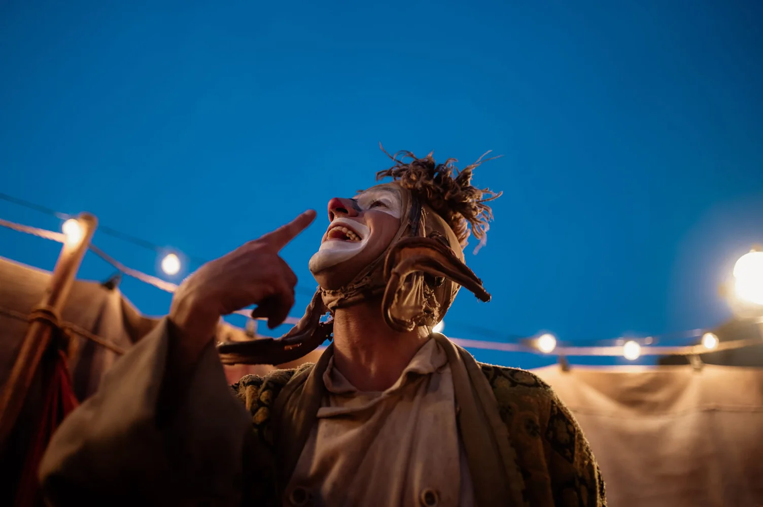 El pallasso Pau Palaus mirant enlaire rient mentre s'assenyala el nas amb el dit índex de la seva mà